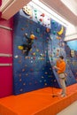 Child wearing a helmet is climbing an indoor artificial wall