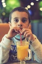 A child wearing a mask in a cafe during a pandemic. A boy in a cafe drinks sea buckthorn tea in a cafe during a pandemic