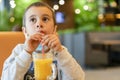 A child wearing a mask in a cafe during a pandemic. A boy in a cafe drinks sea buckthorn tea in a cafe during a pandemic