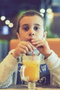 A child wearing a mask in a cafe during a pandemic. A boy in a cafe drinks sea buckthorn tea in a cafe during a pandemic. tioned