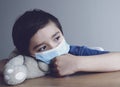 Child wearing medical face mask lying his head on teddy bear with crying tear,Emotional portrait of little boy crying and looking Royalty Free Stock Photo