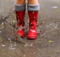 Child wearing red rain boots jumping into a puddle Royalty Free Stock Photo