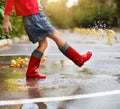 Child wearing red rain boots jumping into a puddle Royalty Free Stock Photo