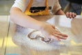 Child wearing yellow apron, playing with flour on table. Close-up picture of hands, drawing shapes on flour. Bakery master class