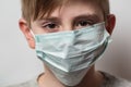 Child wears protective medical mask to protect him from Coronavirus. Boy with medical mask on his face