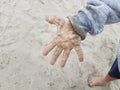 child in wet grey sweatshirt with hand covered in sand Royalty Free Stock Photo