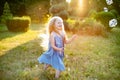 Child whirling, dancing plays on the meadow. Girl having fun with bubbles. Cute little longhair blonde girl dancing with soap Royalty Free Stock Photo