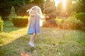 Child whirling, dancing plays on the meadow. Girl having fun with bubbles. Cute little longhair blonde girl dancing with soap Royalty Free Stock Photo