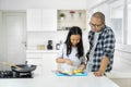 Child whisking eggs while cooking with her father