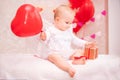 Child with white feathered wings holding a red balloon in the shape of a heart and sees a box with a gift,a symbol of Valentine`s Royalty Free Stock Photo