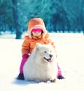 Child and white Samoyed dog lying on snow in winter Royalty Free Stock Photo