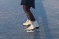 A child in white skates clumsily rides in winter on the ice of a river or lake