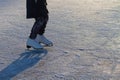 A child in white skates clumsily rides in winter on the ice of a river or lake