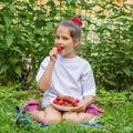 Child in white T-shirt eating strawberries