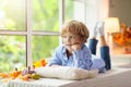 Child at window in autumn. Kids at home in fall Royalty Free Stock Photo