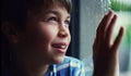 Child, window and smile at rain drops or thinking in home with cold weather, thoughts or future. Male person, boy and Royalty Free Stock Photo