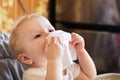 child wipes his nose with white handkerchief. sick child eats sitting on feeding chair. Kid with cold rhinitis. virus and