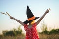 Child in witch hat outdoors, rear view, postcard for the autumn holiday Halloween.