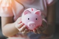 Child woman hand hold pink piggy bank for saving money for education study or investment , Save money concept, daughter hands
