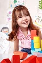 Child with wood block in play room.