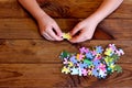 Child working on jigsaw puzzle. Child holding a puzzle in hands. Group of jigsaw puzzles on wooden table