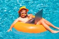 Child working on laptop in summer pool. Little freelancer using computer, remote working in poolside. Royalty Free Stock Photo