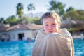 A child wrapped in a towel, basking near the pool. Portrait of a little girl at a tropical resort. The child is resting after Royalty Free Stock Photo