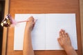 A child writes in an empty notebook on a wooden desk background. Back to school concept. Top view