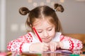 Child writes letter to Santa Claus at home. little girl draws with crayons on background of Christmas devoration Royalty Free Stock Photo