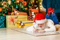 Child writes a letter to Santa Claus lying on the floor under the Christmas tree Royalty Free Stock Photo