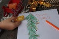 Child writes letter to Santa and draw a Christmas tree. Royalty Free Stock Photo