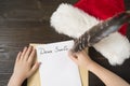 Child writes letter to Santa. Hat of Santa, wooden background