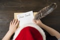 Child writes letter to Santa In santa`s hat. Wooden background. Christmas concept Royalty Free Stock Photo