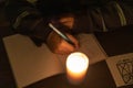 A child writes in a notebook by candlelight