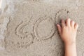 A child is writing a finger on the sand of the word SOS Royalty Free Stock Photo