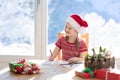 Child writing letter to Santa on Christmas eve. Kids write Xmas present wish list. Little girl sitting in decorated living room Royalty Free Stock Photo