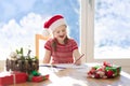 Child writing letter to Santa on Christmas eve. Kids write Xmas present wish list. Little girl sitting in decorated living room Royalty Free Stock Photo