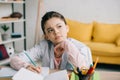 Child writing in notebook and looking away while doing schoolwork at home Royalty Free Stock Photo