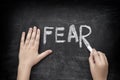 Child writing word Fear on blackboard