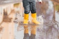 Child& x27;s feet in yellow rubber boots jumping over a puddle in the rain Royalty Free Stock Photo