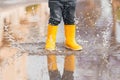 Child& x27;s feet in yellow rubber boots jumping over a puddle in the rain Royalty Free Stock Photo