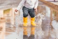 Child& x27;s feet in yellow rubber boots jumping over a puddle in the rain Royalty Free Stock Photo