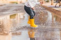 Child& x27;s feet in yellow rubber boots jumping over a puddle in the rain Royalty Free Stock Photo
