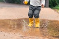 Child& x27;s feet in yellow rubber boots jumping over a puddle in the rain Royalty Free Stock Photo