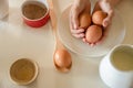 child& x27;s hand holding eggs, baking ingredients on white kitchen table, baking at home with kids, cake in a mug Royalty Free Stock Photo