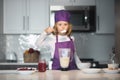 Child 7-8 years old in chef hat and apron. Chef child in apron and chef hat cooking at kitchen. Healthy food. Royalty Free Stock Photo
