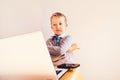 Child 5 years old working on a laptop with an angry face when business failing, humor image