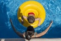 Child with a yellow float next to a woman in a pool. Royalty Free Stock Photo