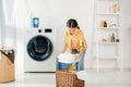 child in yellow shirt near washer and ladder putting towels in basket