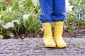 Child in yellow wellington boots in garden